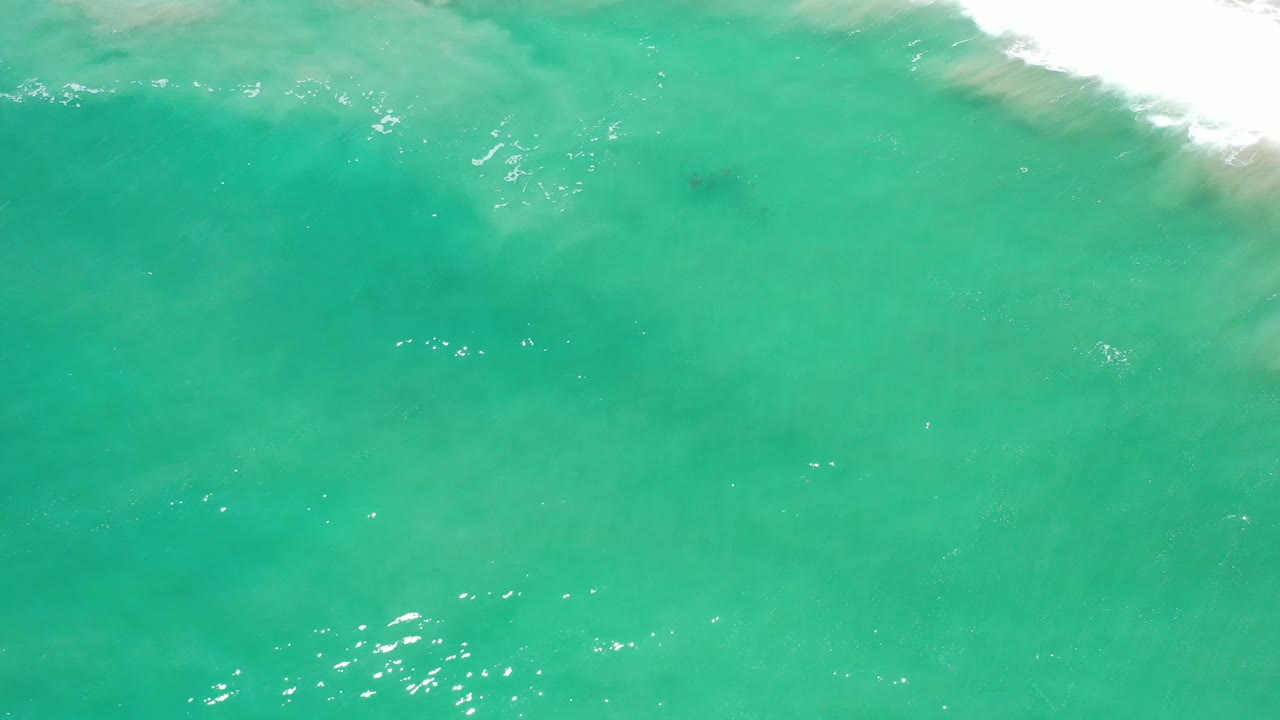Wide field of turquoise water with faint underwater patches.