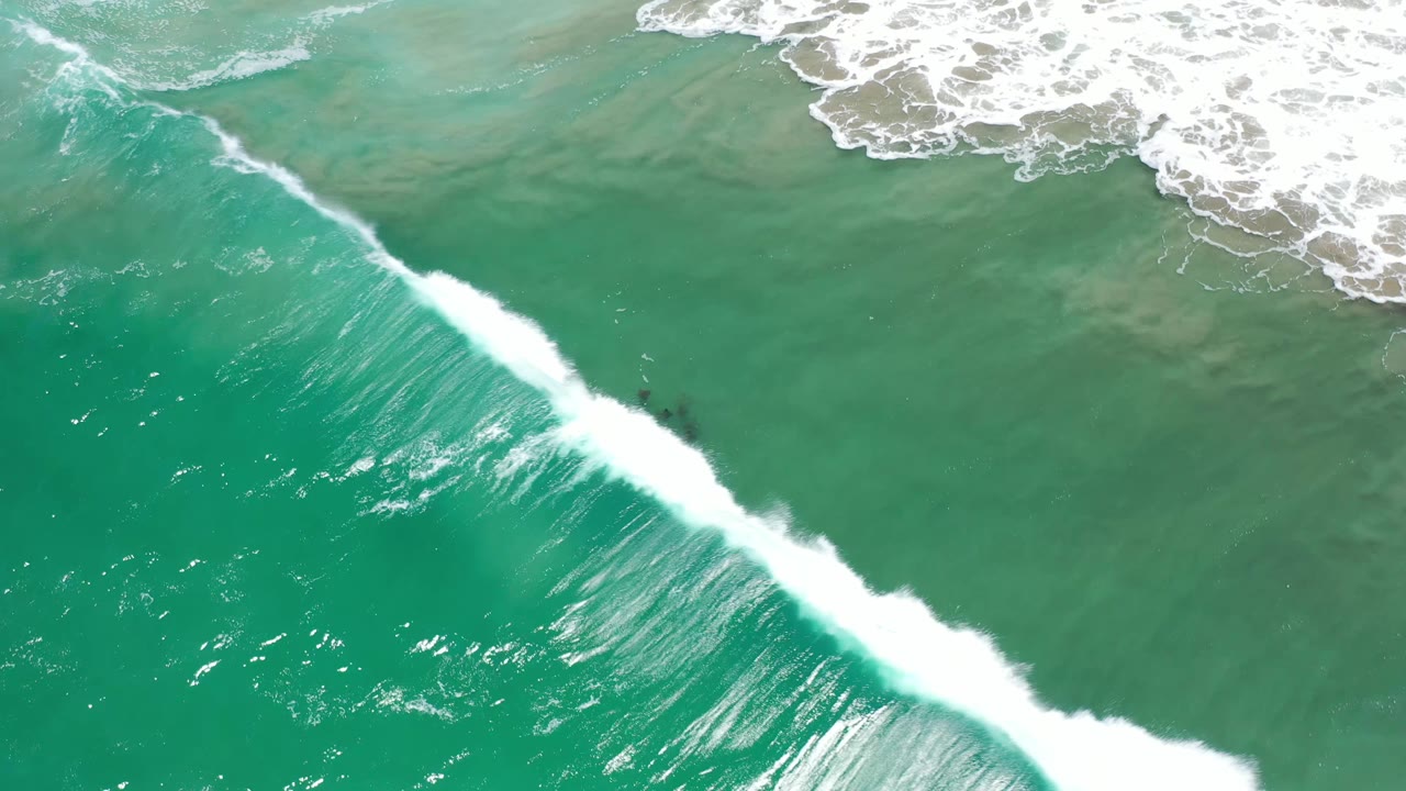 The wave ridge in Los Cabos, Mexico grows brighter and thicker as it cuts diagonally across green ocean water, with no visible people.