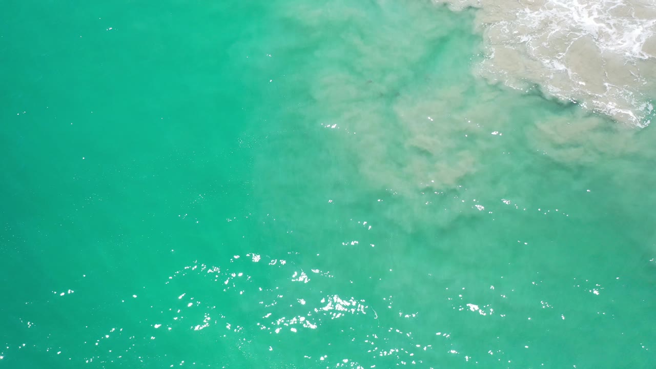 Clear green sea with cloudy pale surf near the top