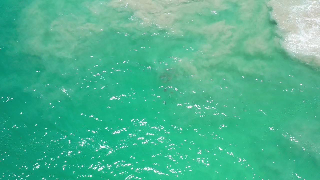 Turquoise ocean water with white surf at the upper right.