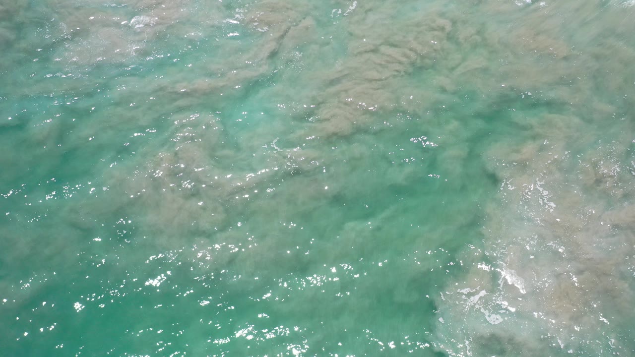 Clear turquoise water in Los Cabos, Mexico shows pale sand suspended beneath small ripples, with no visible people.
