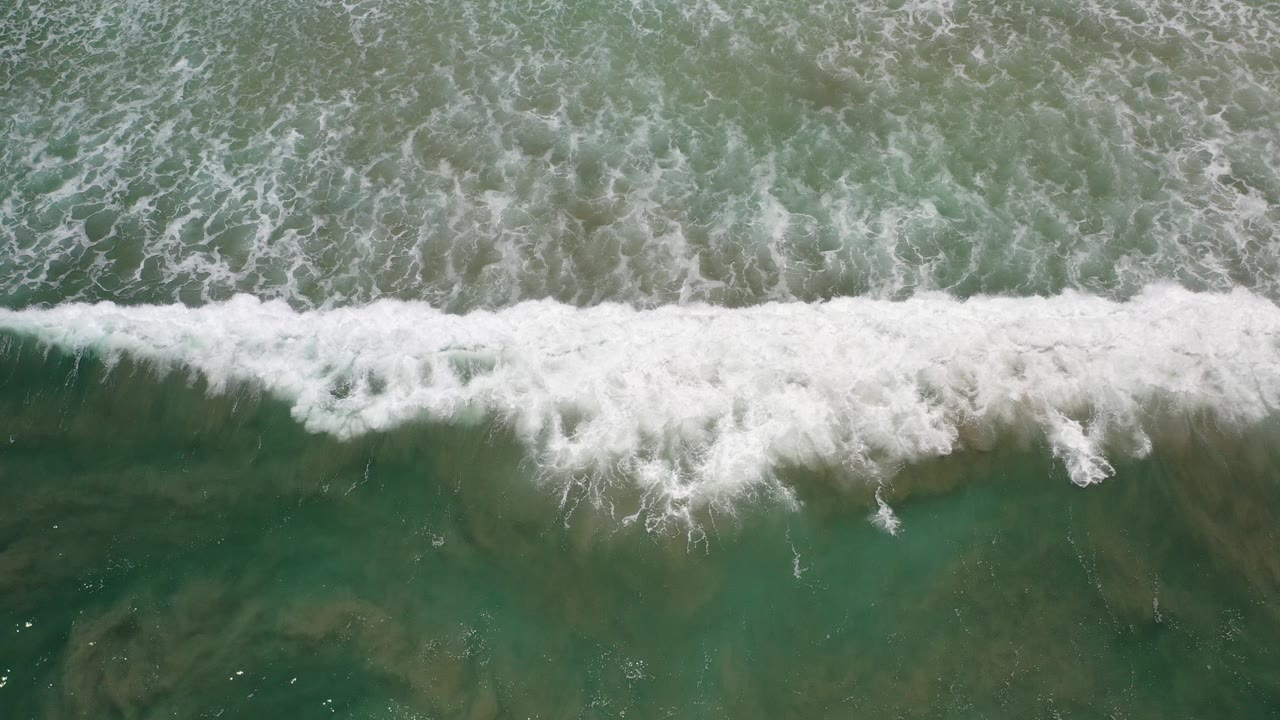 Overhead surf line breaking across green ocean water