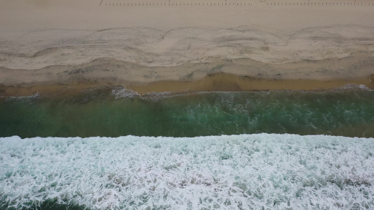 Aerial beach shoreline with surf and dark wet sand