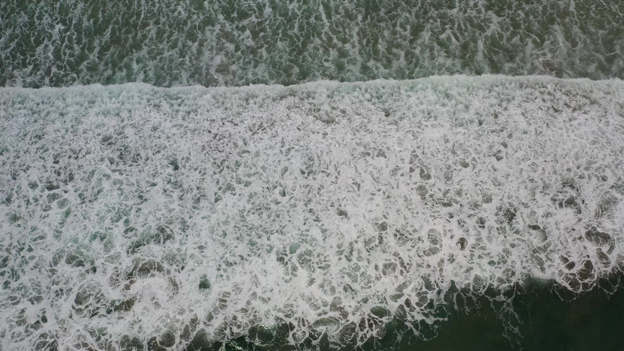 Overhead view of white seawaves covering dark green water in Los Cabos, Mexico, with no visible people.