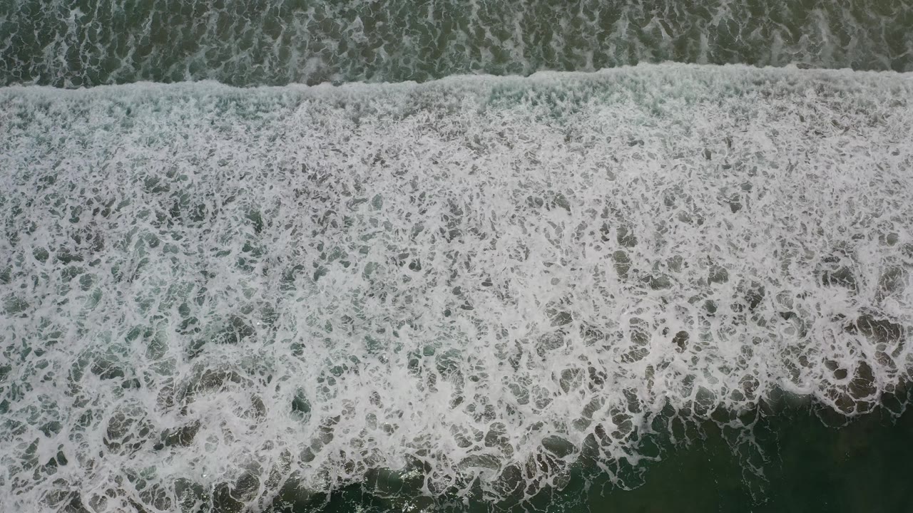 Wide band of whitewater crossing darker ocean beneath it.