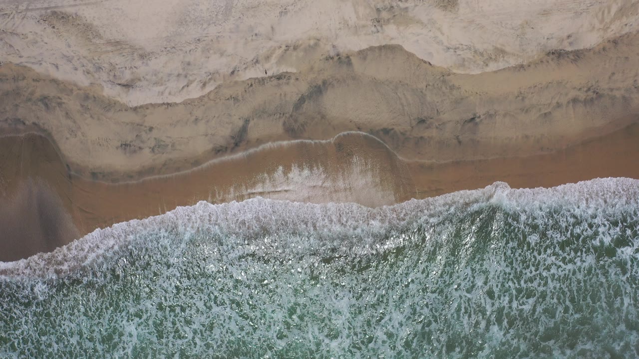 Overhead surf washing onto pale sand