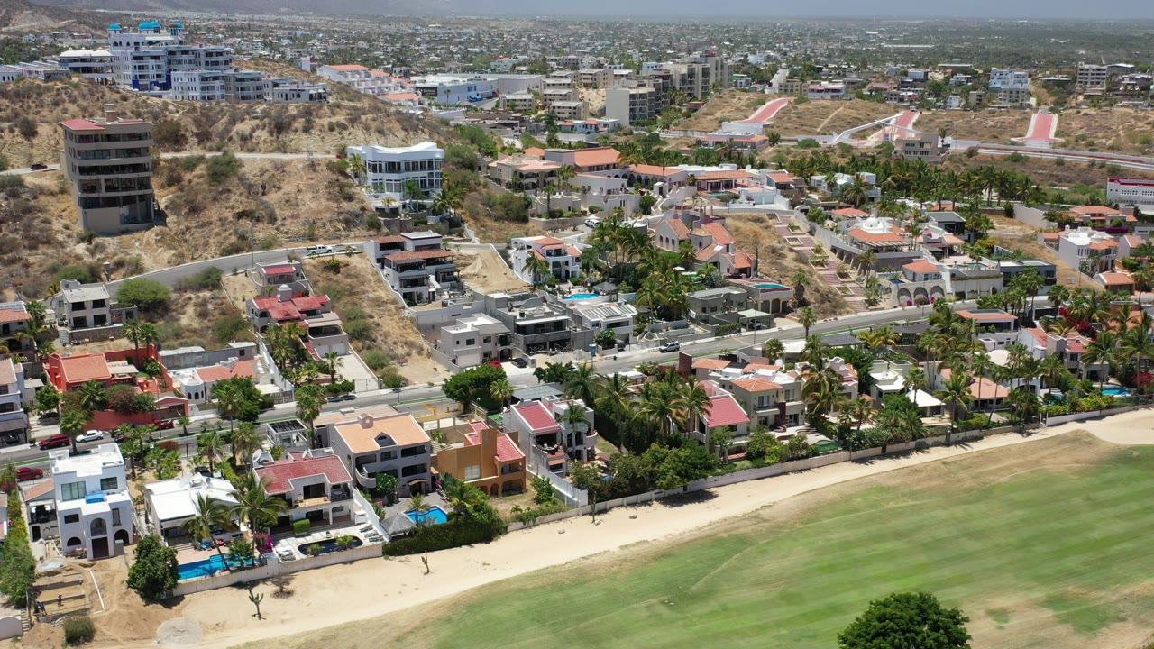 Aerial view of hillside homes beside a broad green lawn.
