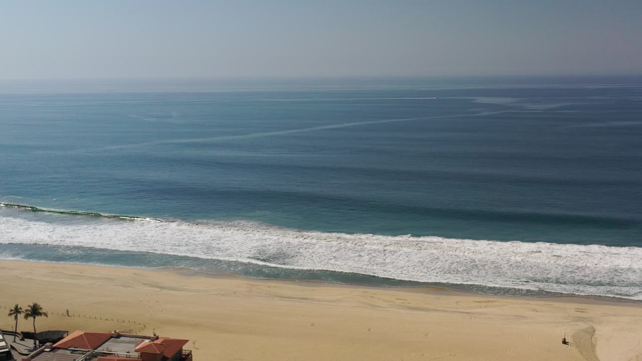 Aerial view of ocean waves breaking onto a sandy beach