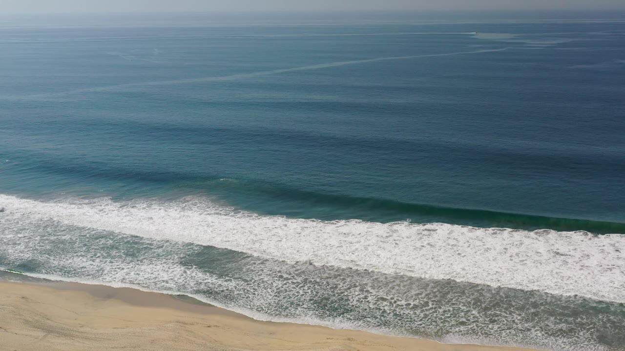 Long white breaker across blue-green ocean water