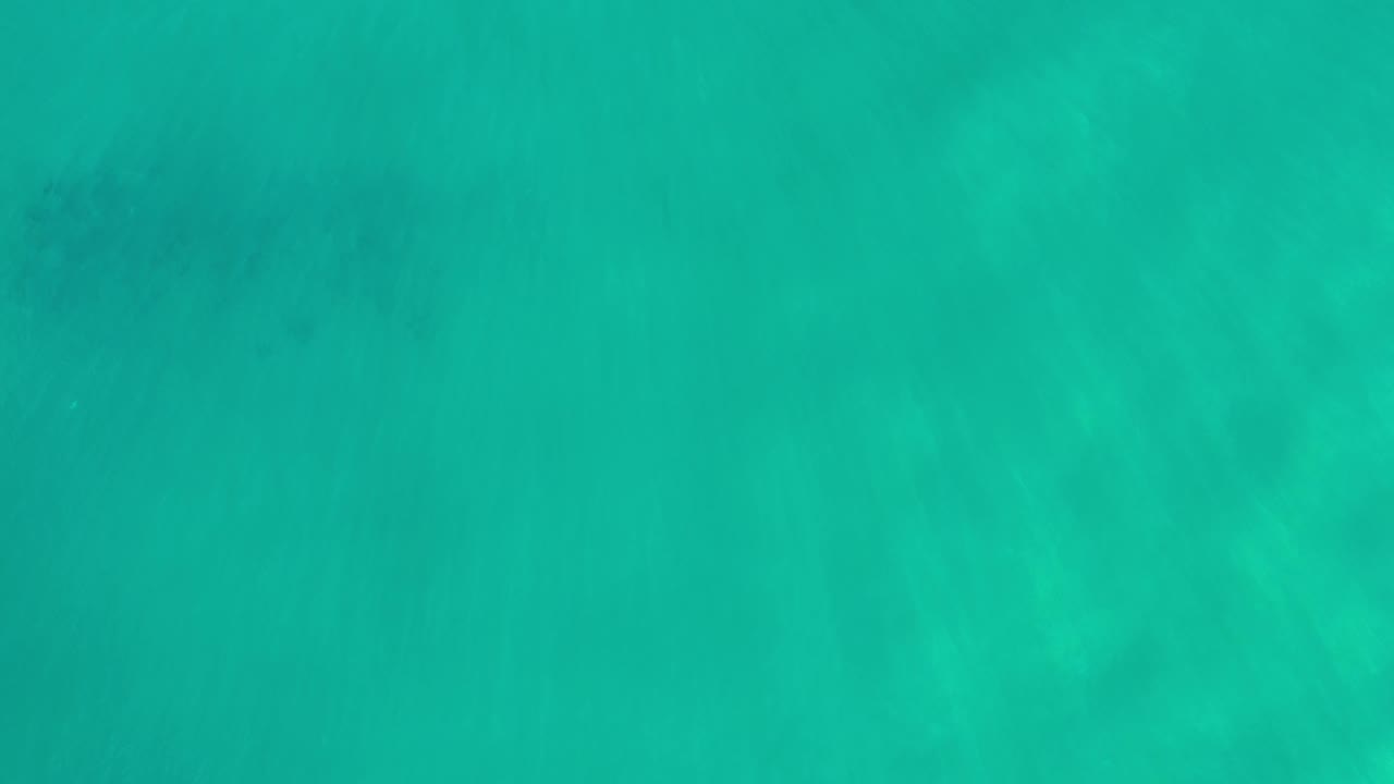 Clear emerald water fills the frame in Los Cabos, Mexico, with faint darker areas under the surface and no visible people.