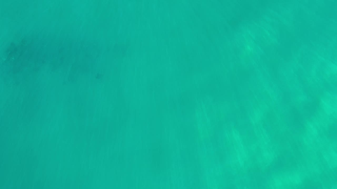 Shallow turquoise sea with pale floor texture beneath