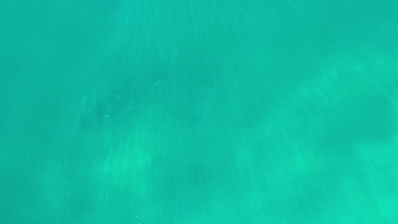 Blue-green Los Cabos ocean water shows broad soft darker areas beneath the surface, with no visible land, boats, or people.