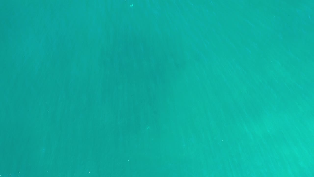 Overhead view of clear turquoise seawater in Los Cabos, Mexico, with faint seabed streaks and no visible people.