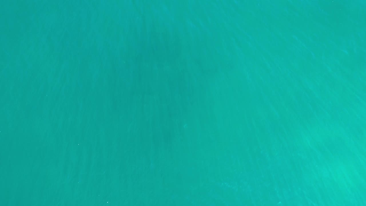 Open turquoise ocean surface with subtle underwater streaking.