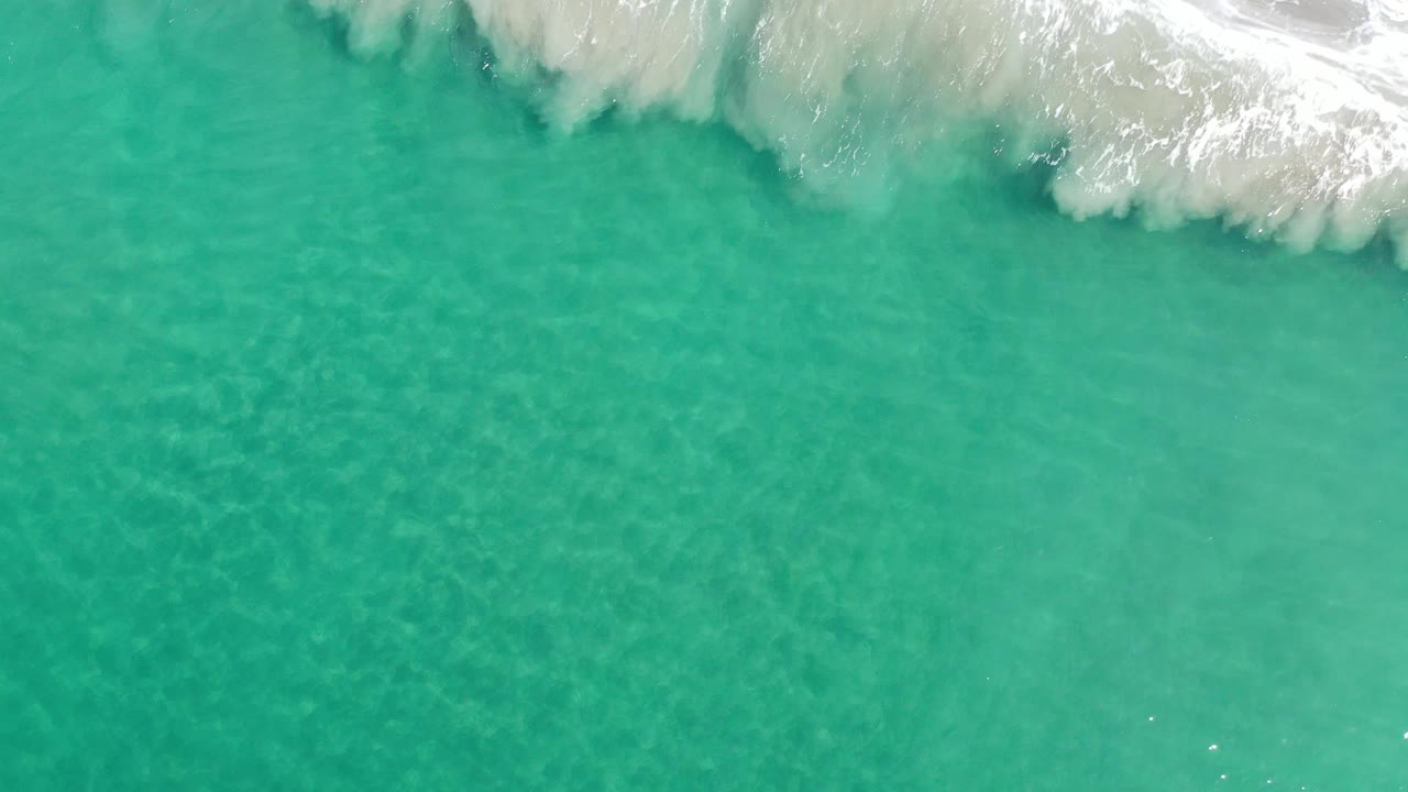 Clear teal water below a breaking white wave at the top