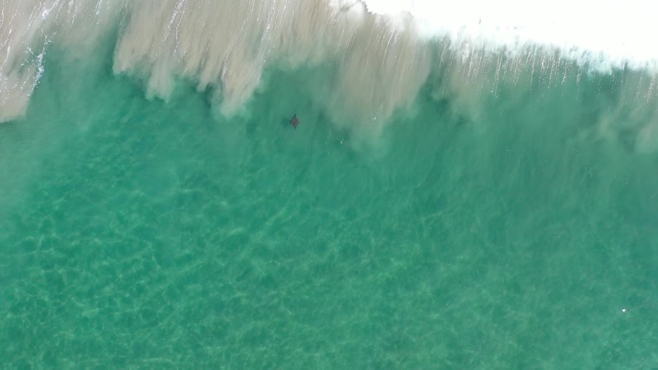 Foam spreading over turquoise shallow water