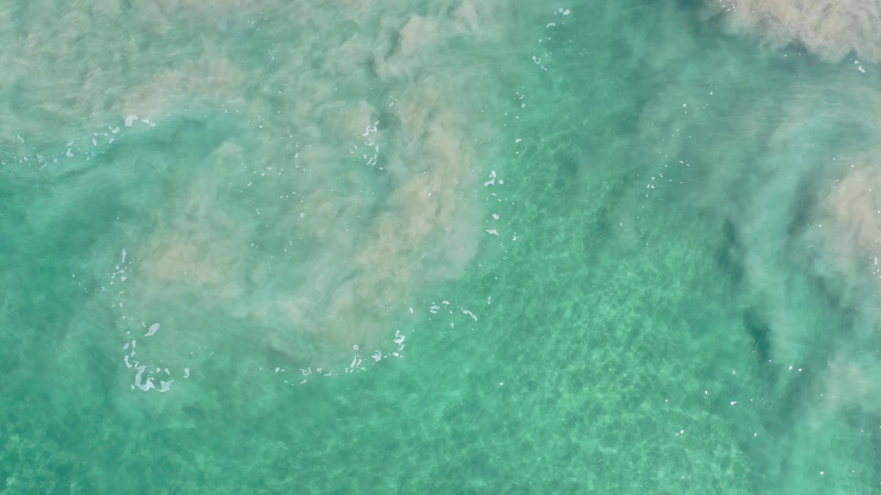 Aerial ocean surface with pale sediment swirl