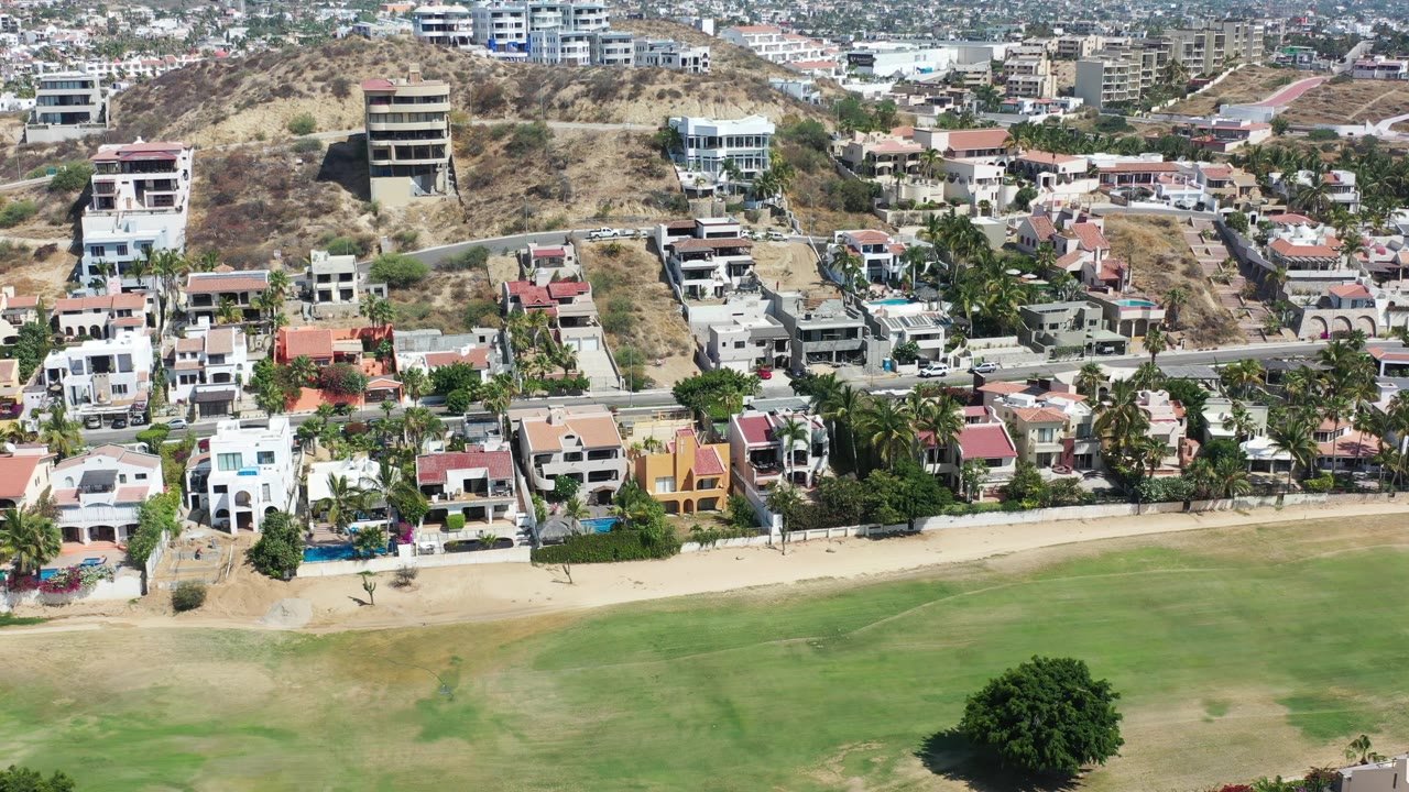 Drone view over Los Cabos homes and open green ground