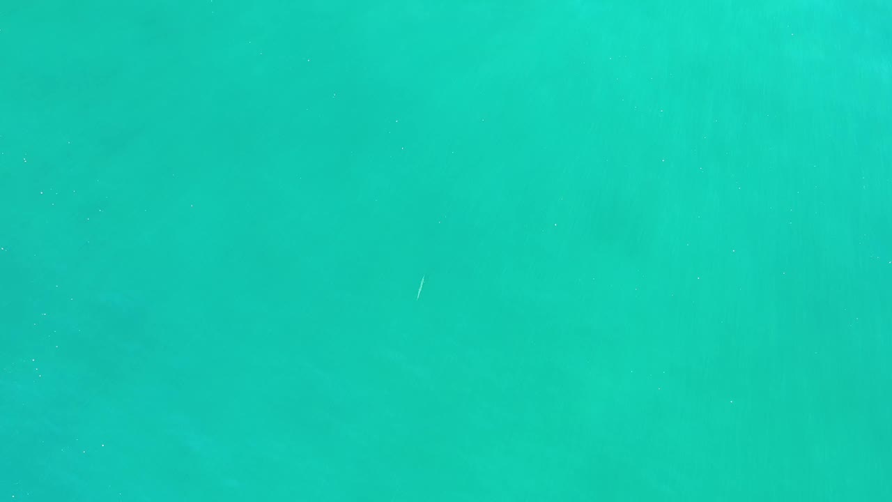 A nearly full-frame view of clear Los Cabos water shows faint darker patches beneath the turquoise surface and no visible people.