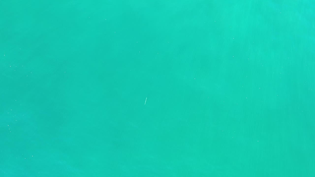 Turquoise water surface with small bright streaks.