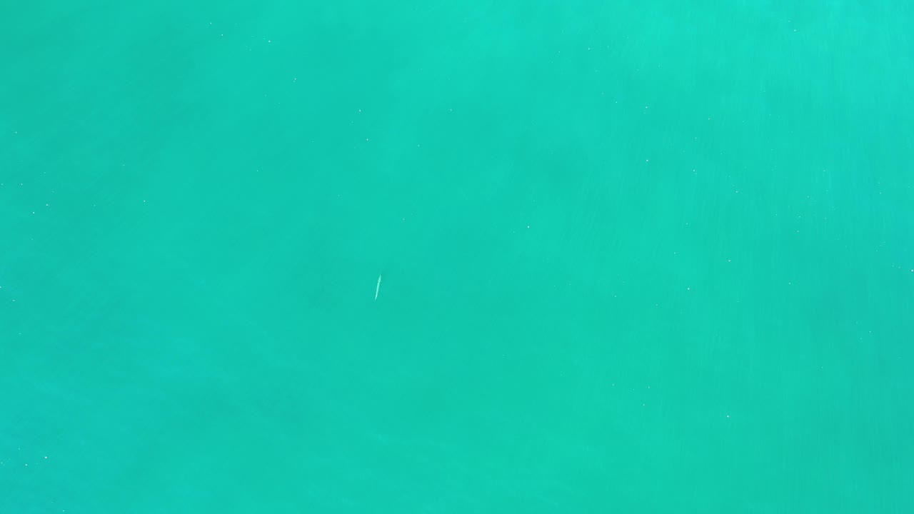 A near-vertical view of turquoise water in Los Cabos, Mexico, showing soft horizontal tonal bands and no visible people.