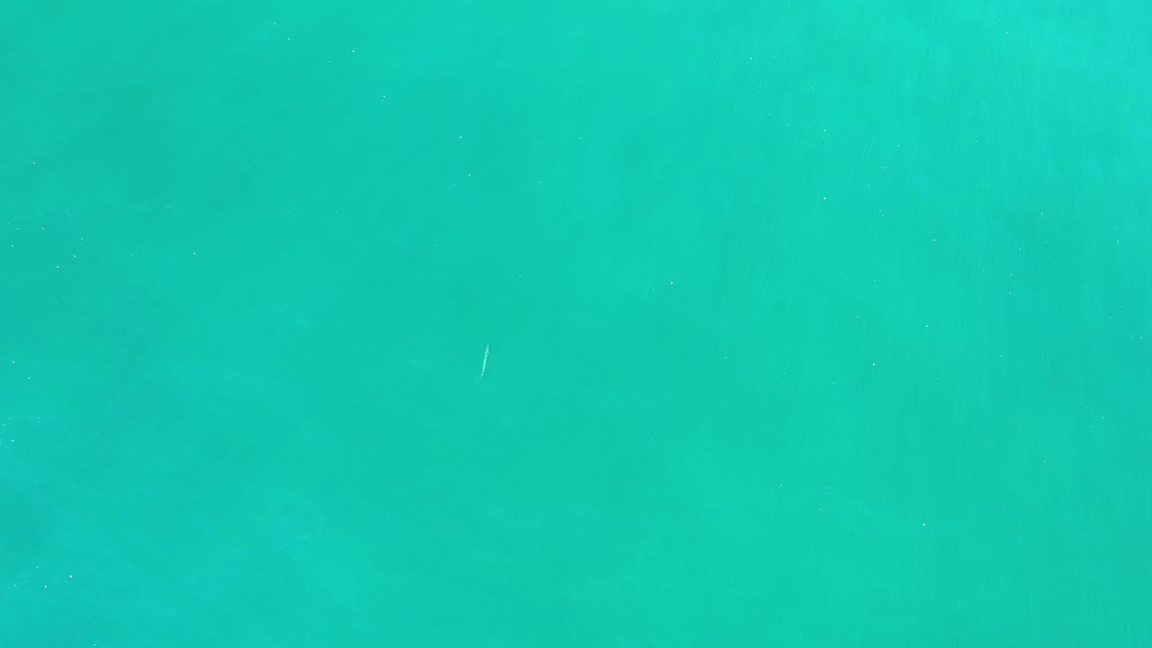 Clear blue-green water with tiny white flecks