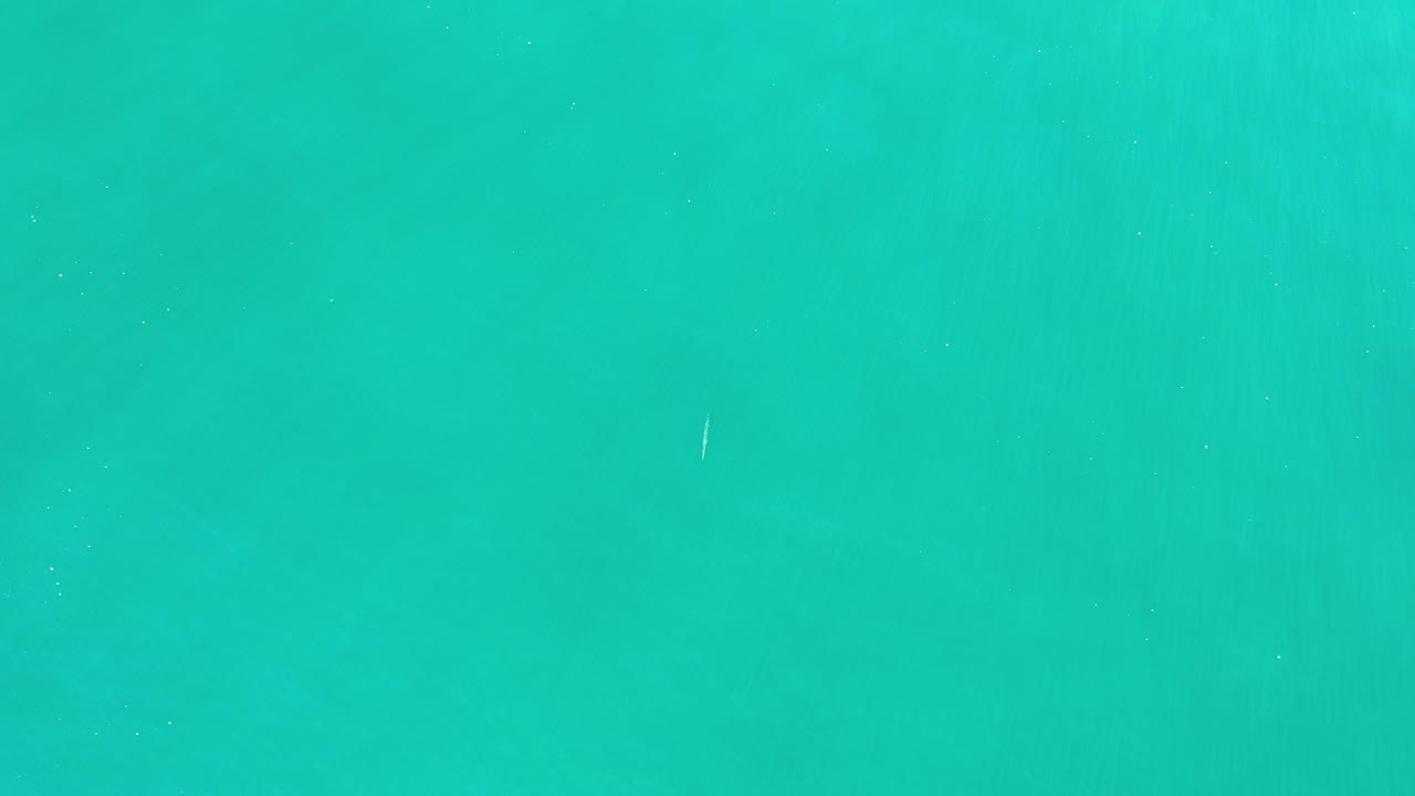 Overhead view of clear turquoise-green ocean water in Los Cabos, Mexico, with faint surface texture and no visible people.