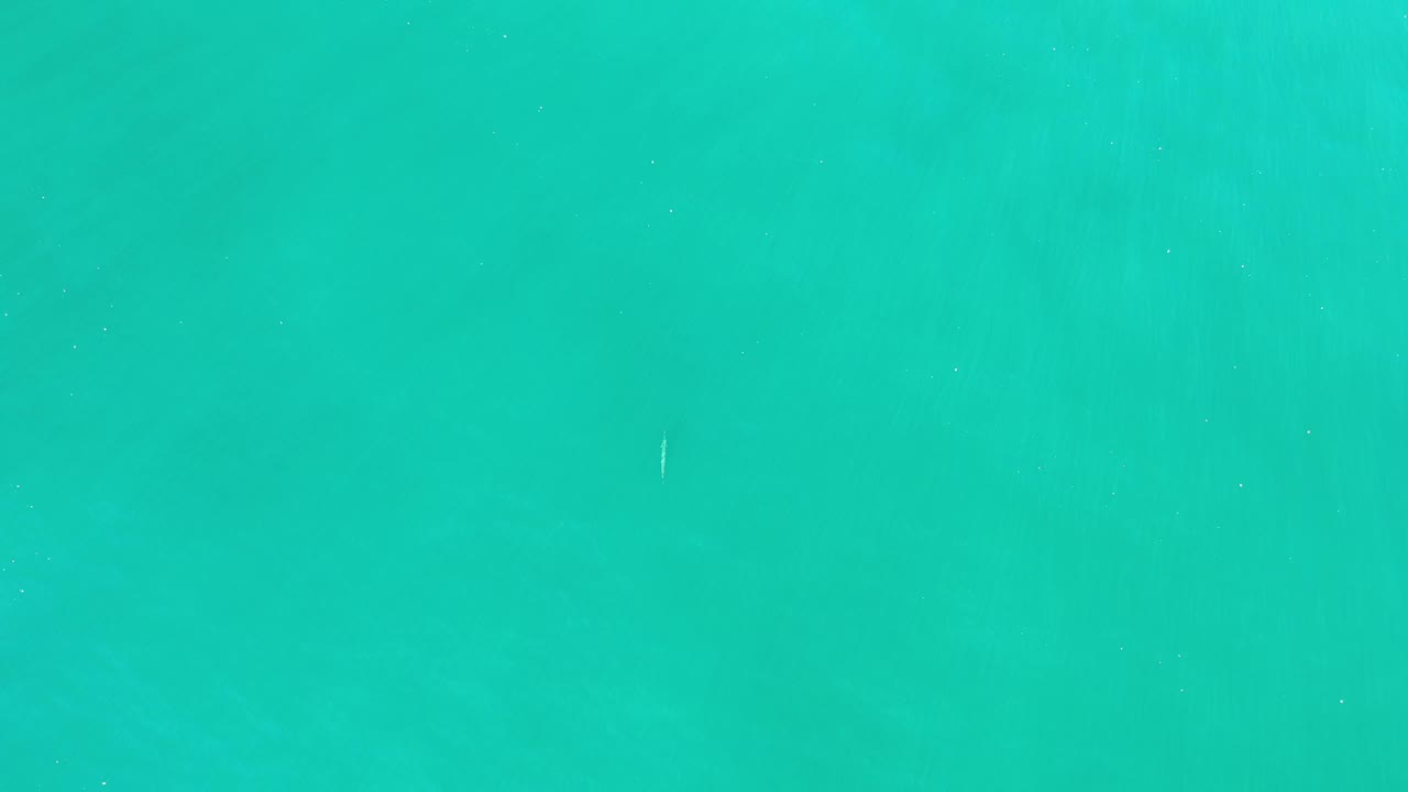 Blue-green water in Los Cabos, Mexico fills the frame with soft ripple texture, a small pale streak near the top, and no visible people.