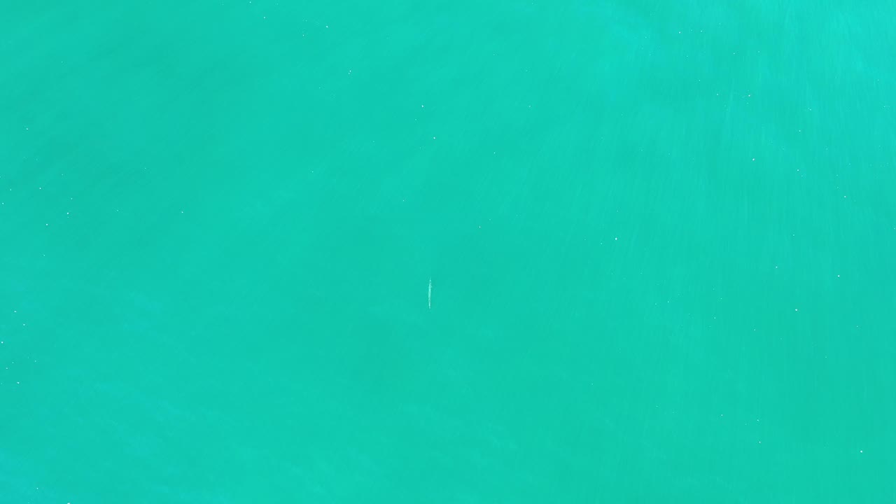 Open turquoise water with faint waves and a small white streak.