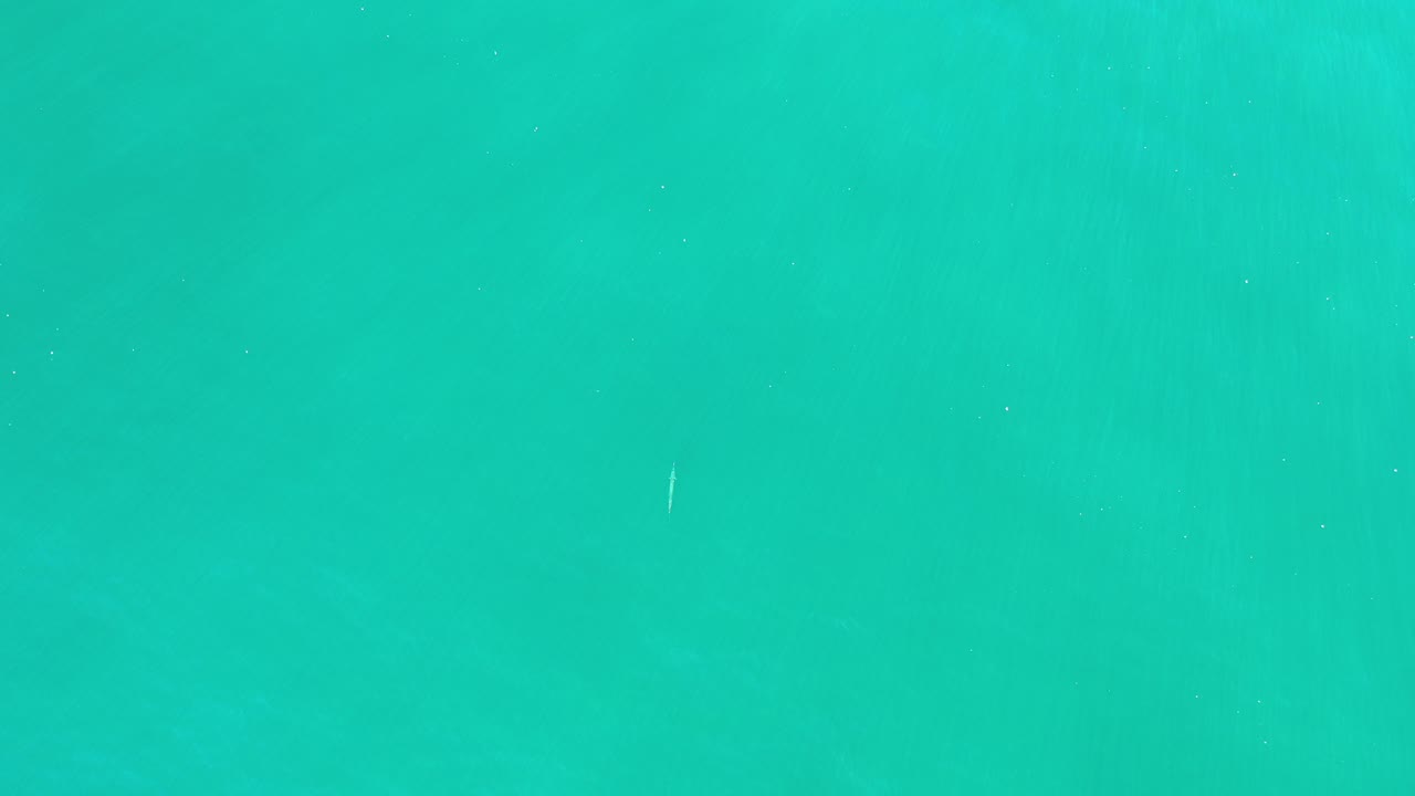 High aerial view over turquoise ocean and soft mist in Los Cabos, Mexico, with no visible people and no shoreline in frame.
