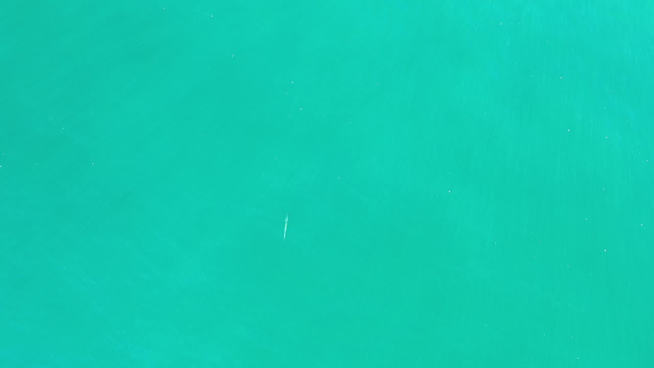 Downward view of turquoise-green ocean water in Los Cabos, Mexico, with faint wave bands and no visible people.
