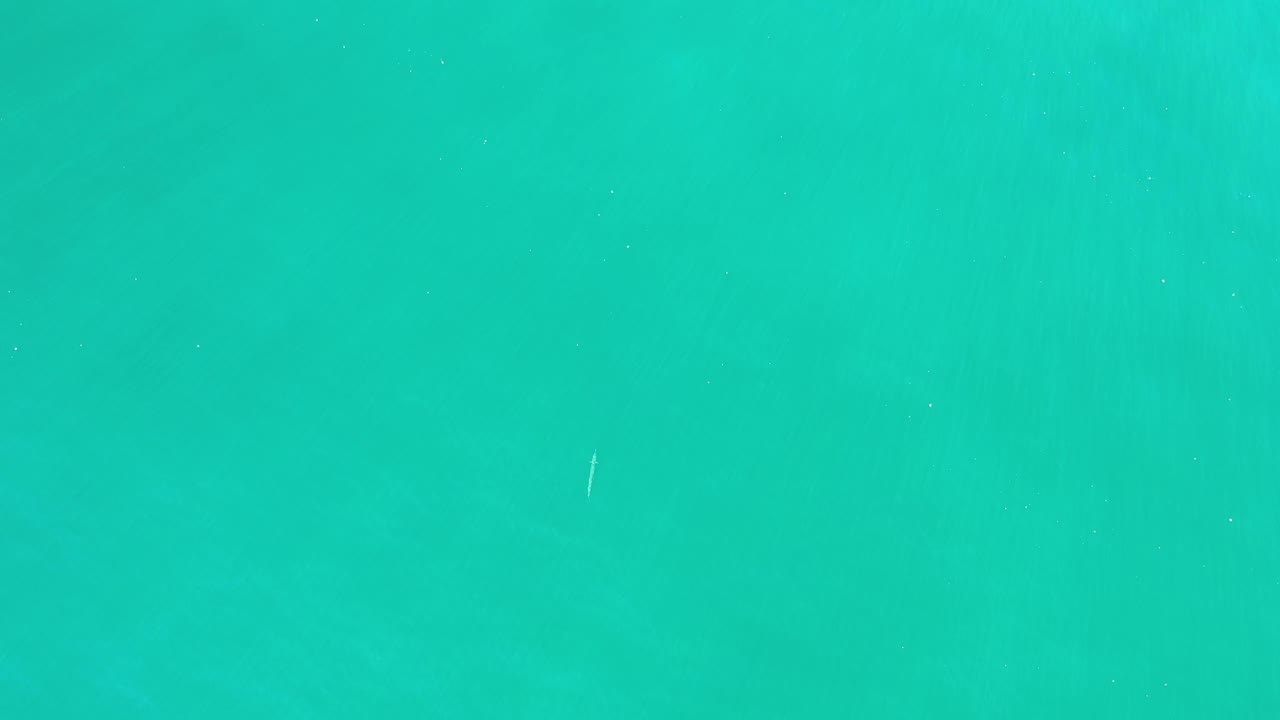 Clear green water fills the frame in Los Cabos, Mexico, with slightly darker patches under the rippling surface and no visible people.