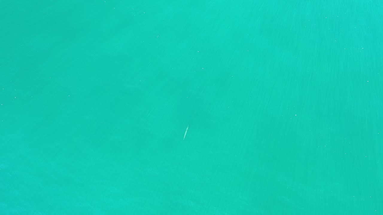 Turquoise water in Los Cabos, Mexico, fills the frame with a small pale floating object near the upper-left area and no visible people.