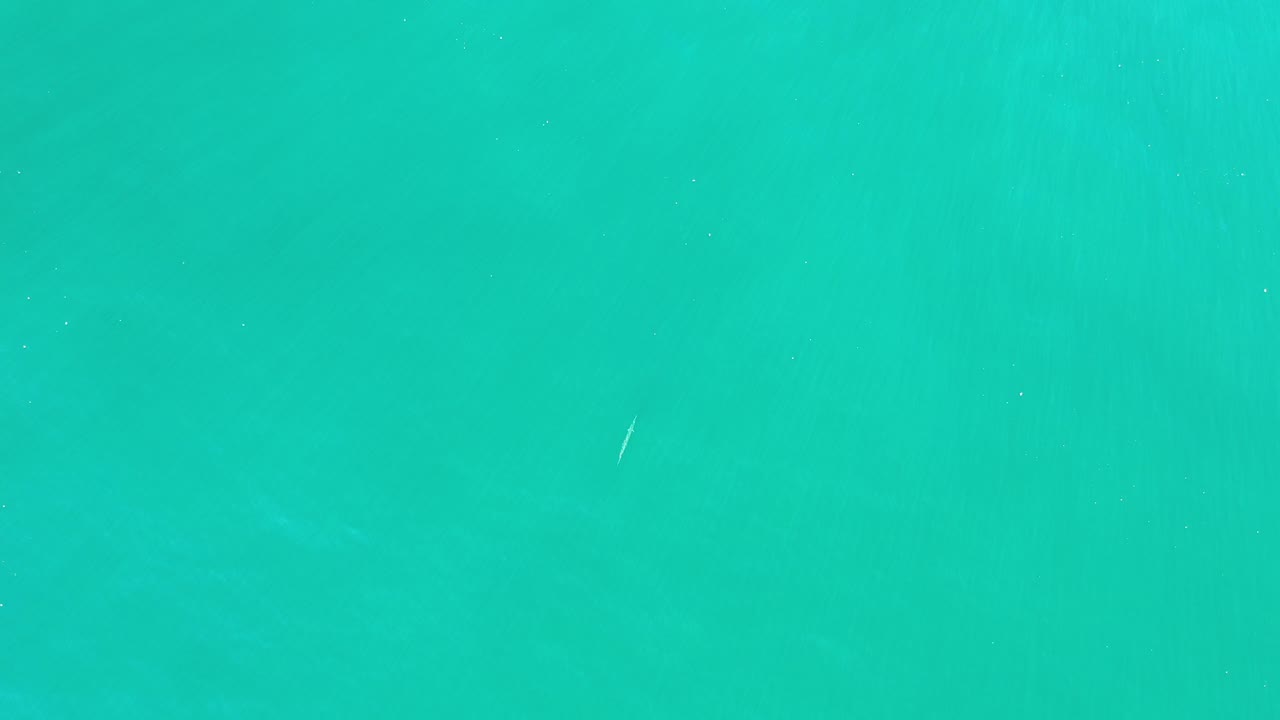 Overhead view of turquoise-green ocean water in Los Cabos, Mexico, with a few pale wave marks and no visible people.
