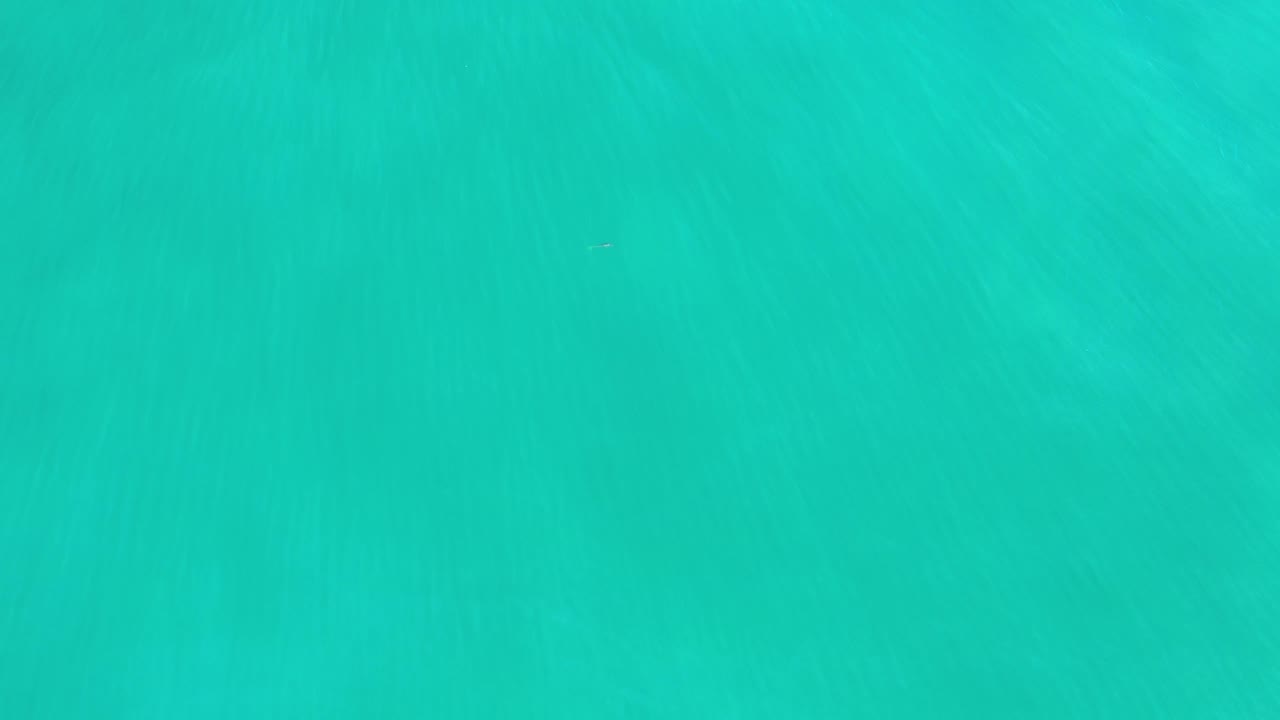 Blue-green water fills the Los Cabos frame, with slightly darker ripples near the upper area and no visible people.
