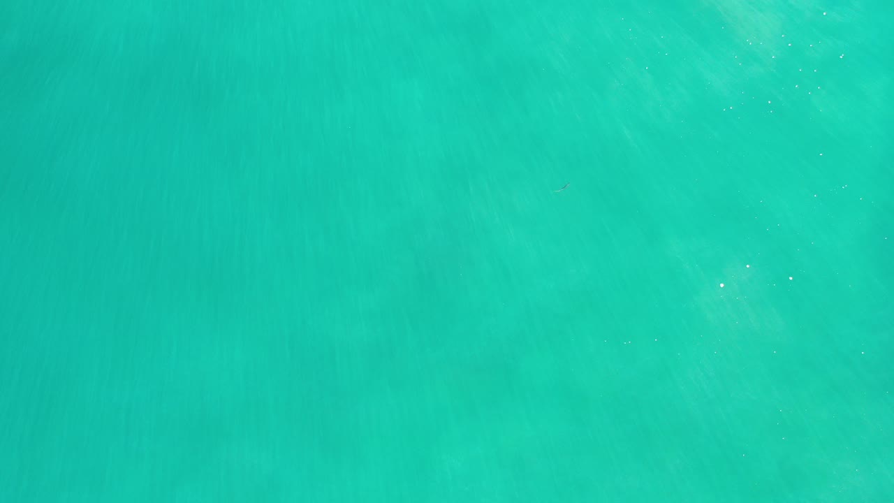 Overhead view of turquoise green water in Los Cabos, Mexico, with faint underwater patches and no visible people.