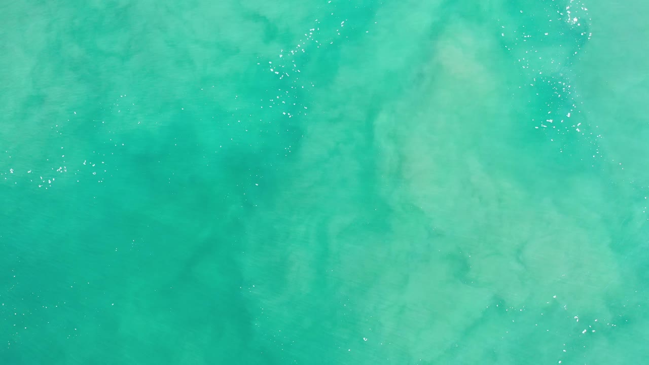 Aerial view of blue-green sea with cloudy streaks