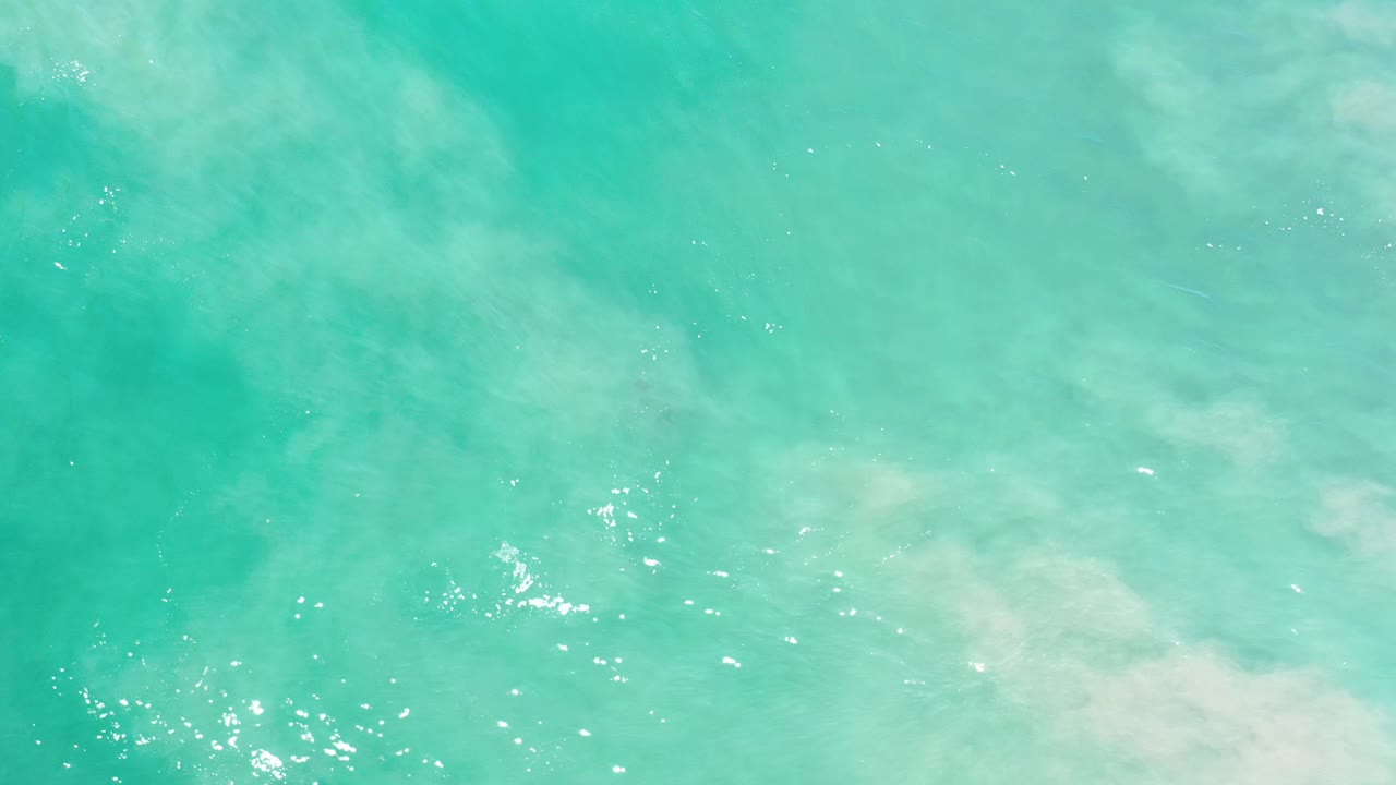 Overhead view of turquoise ocean water in Los Cabos, Mexico, with pale submerged foam patterns and no visible people.