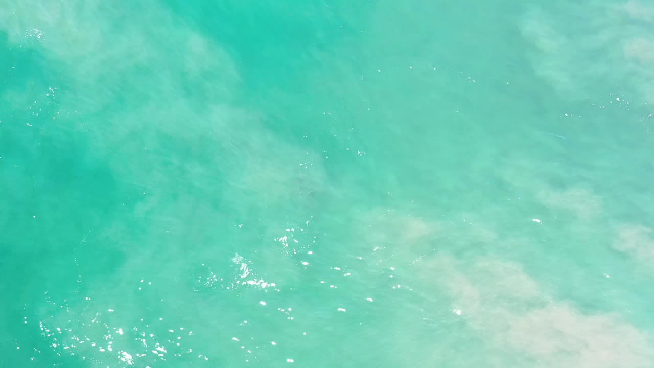 Blue-green ocean surface in Los Cabos, Mexico, with small bright reflections near the lower center and no visible people.