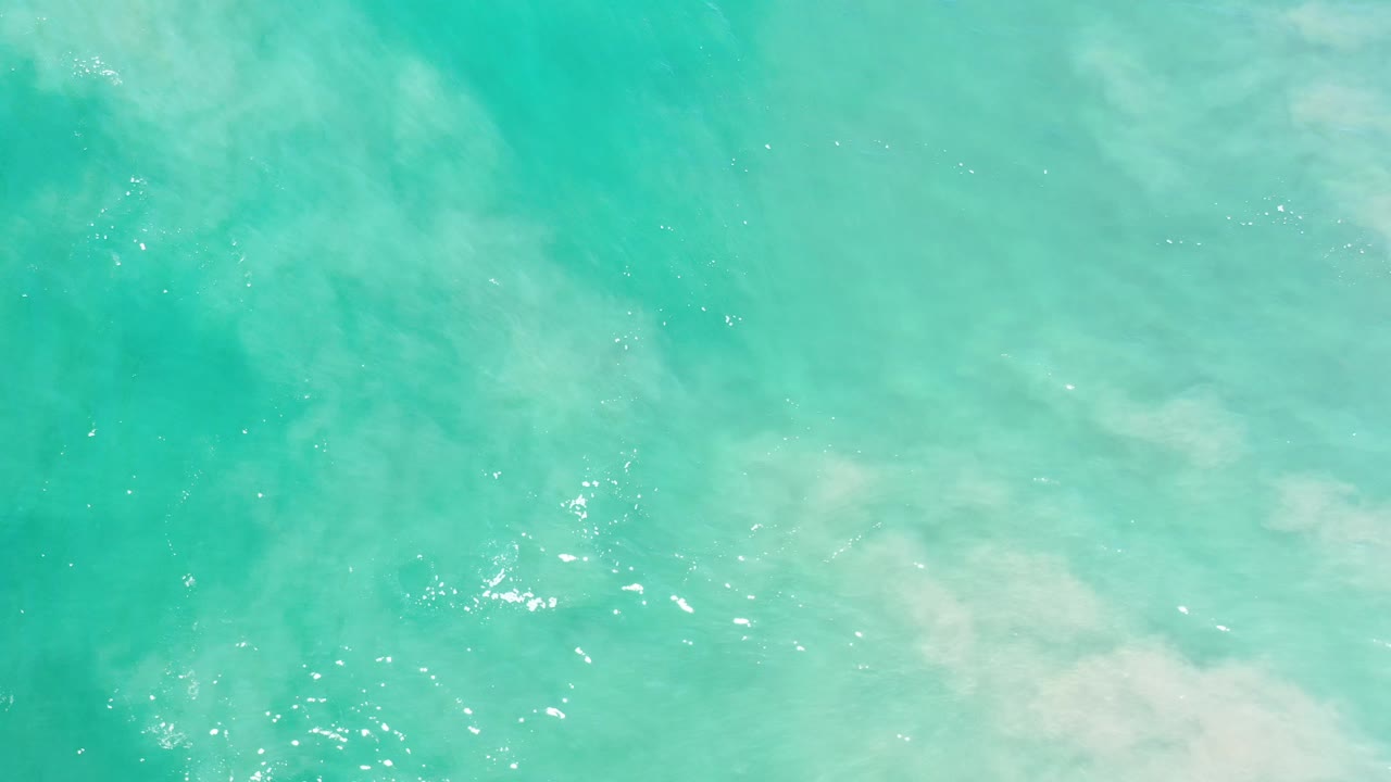 Turquoise sea surface with soft white wash drifting across the right side.
