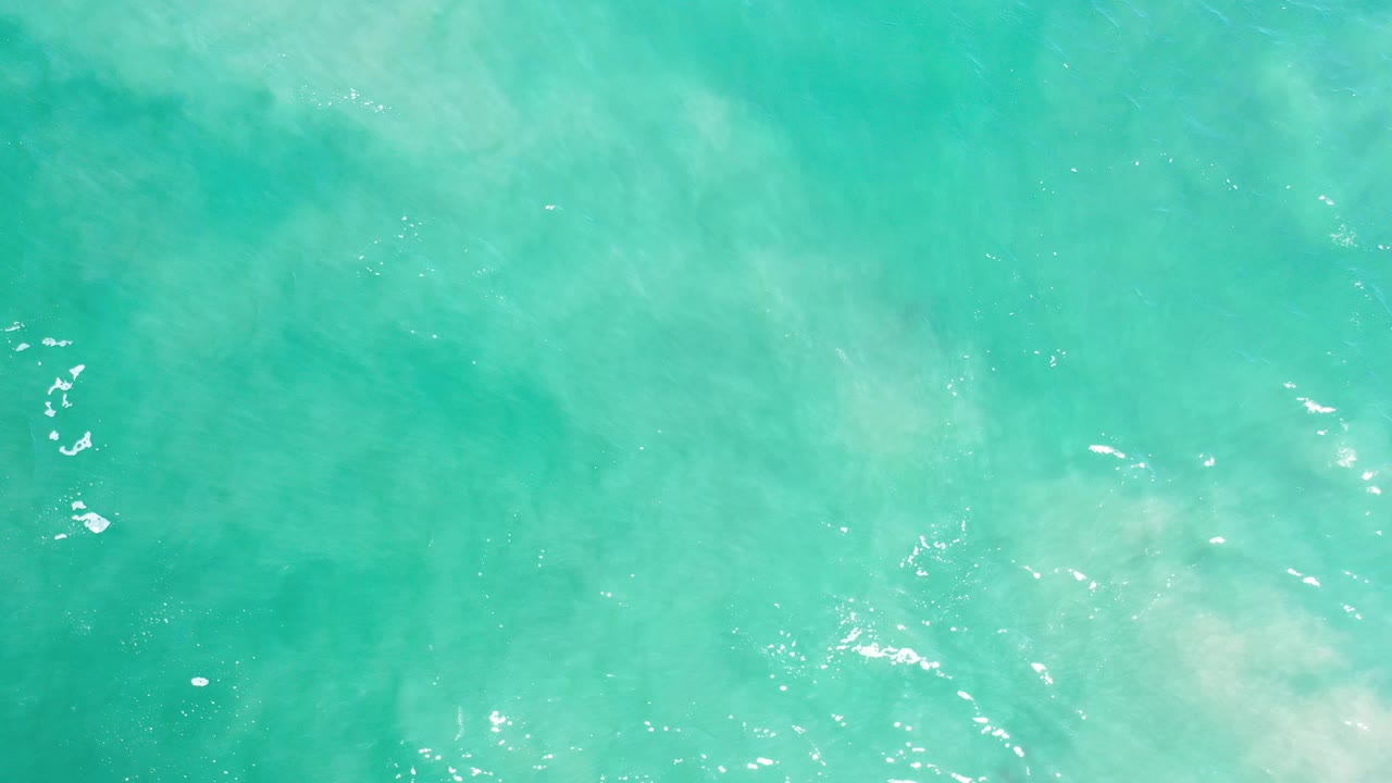 Turquoise ocean water with soft white wave wash.