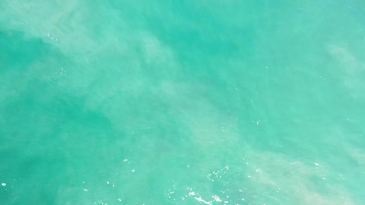 Overhead Los Cabos ocean surface with soft white ripples near the lower edge and no visible people or boats.