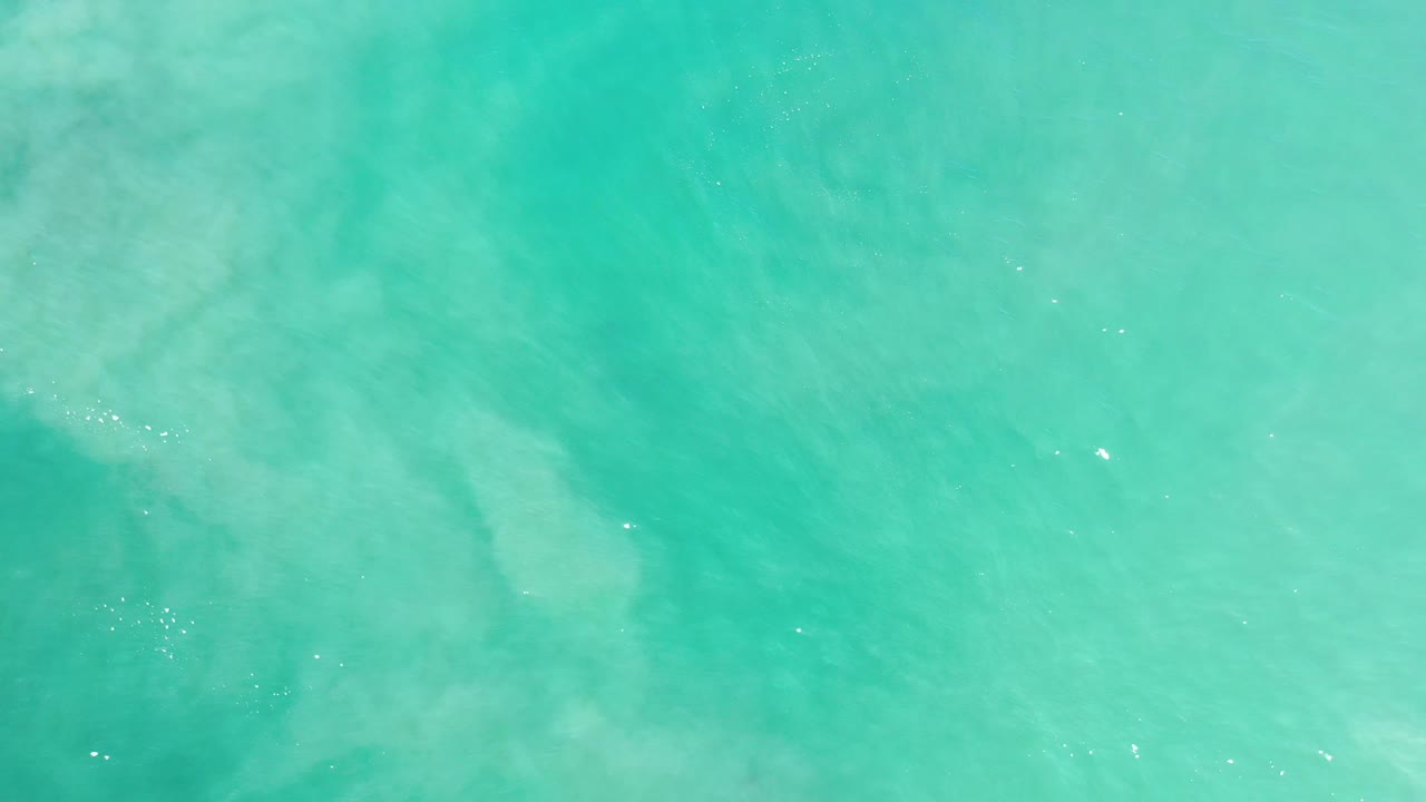 Turquoise water with faint cloudy patterns under the surface.