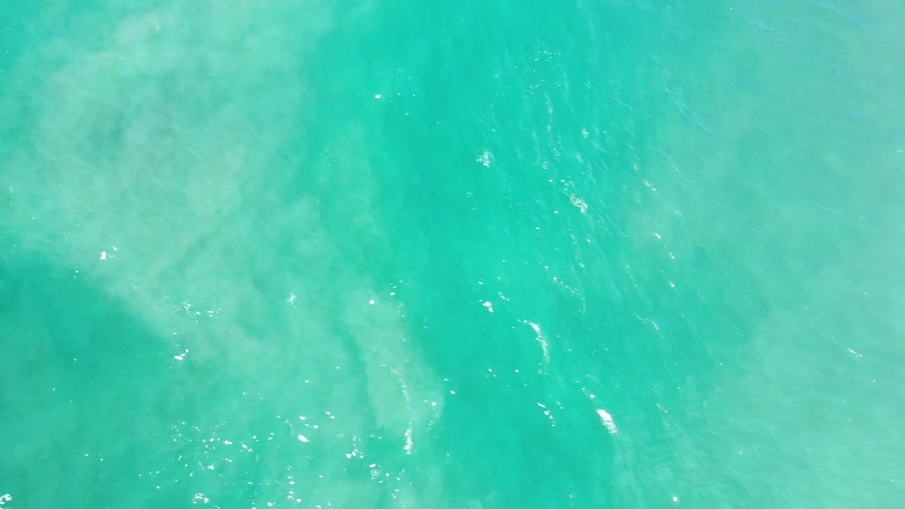Turquoise green ocean surface with pale underwater turbulence.