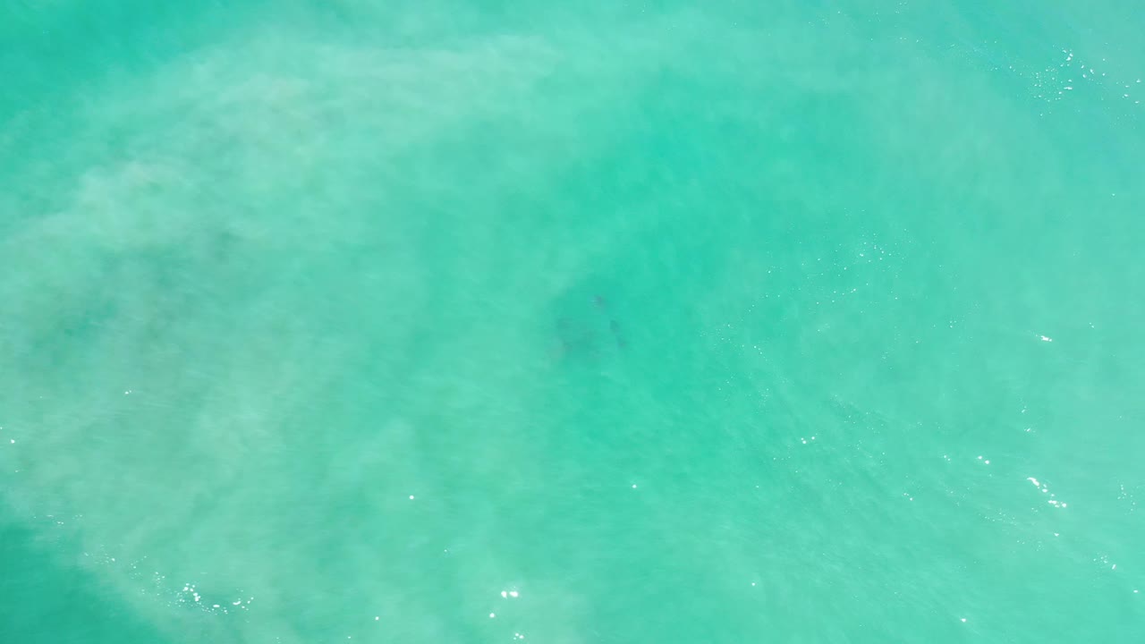 Turquoise seawater in Los Cabos, Mexico, shows faint ripples, cloudy shallows, and no visible people.