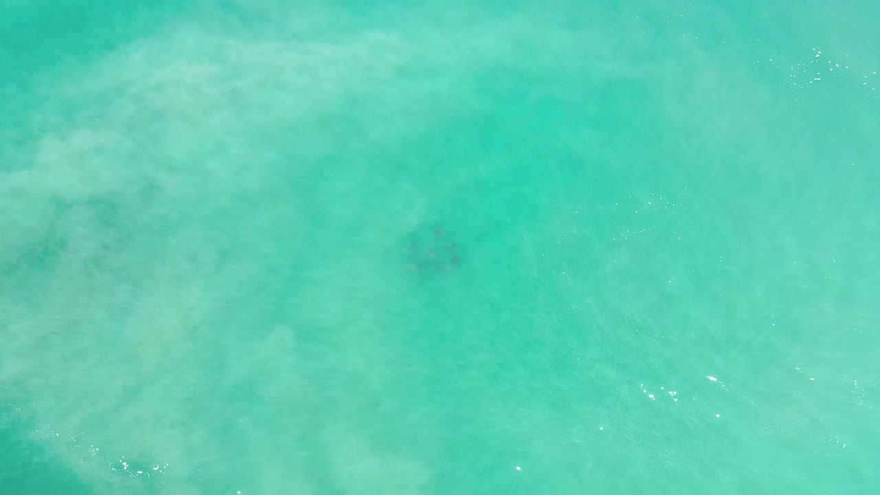 Bright turquoise water with scattered sun reflections.