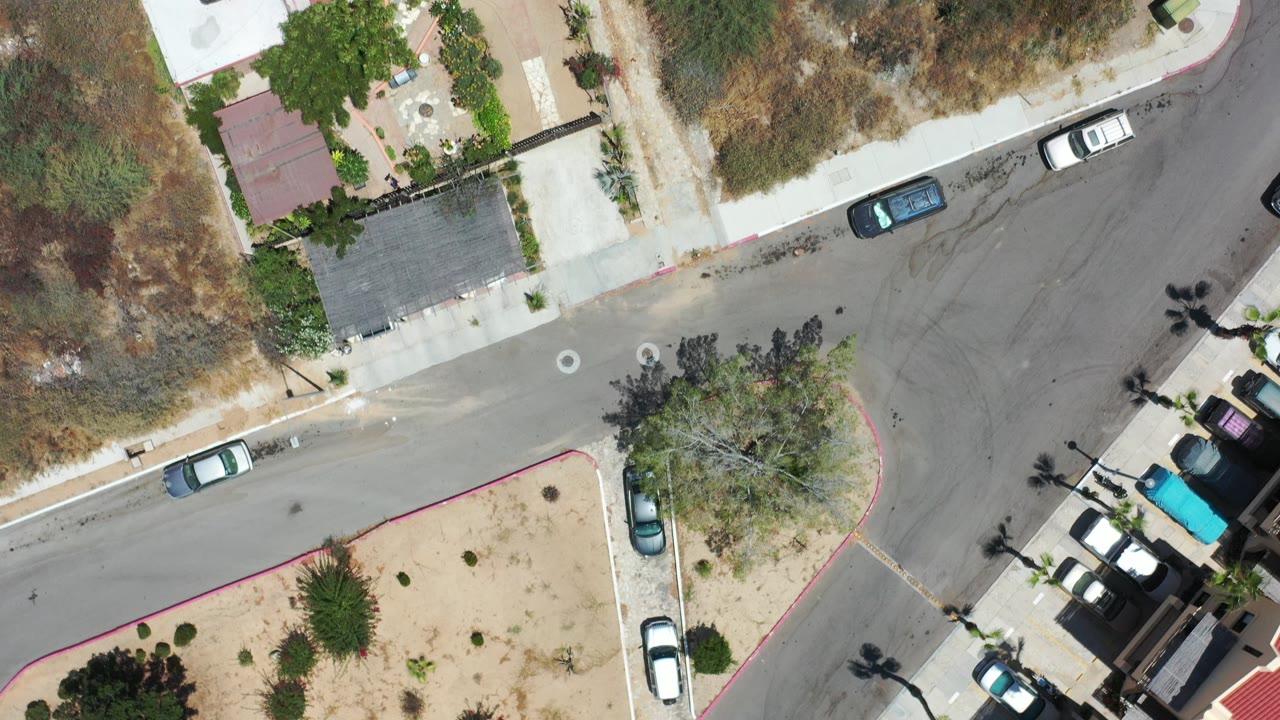 Overhead street corner with parked cars and dry lots.