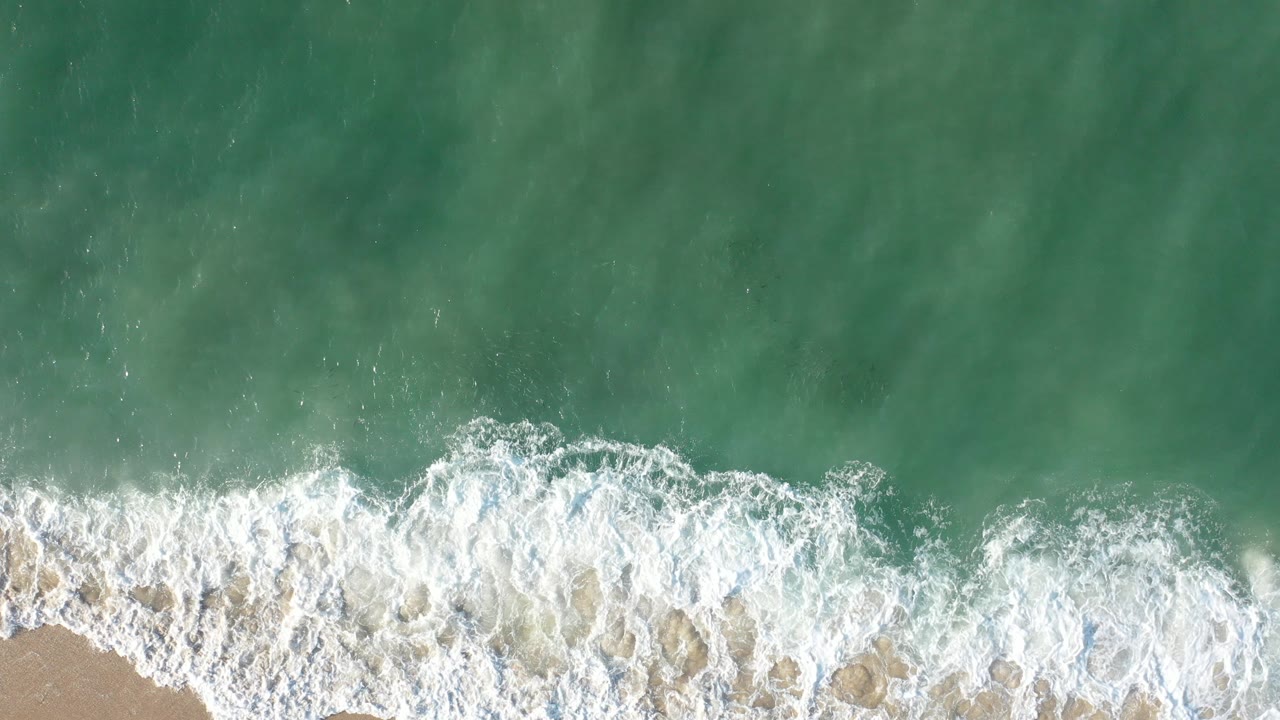 Overhead surf breaking onto a narrow sandy beach