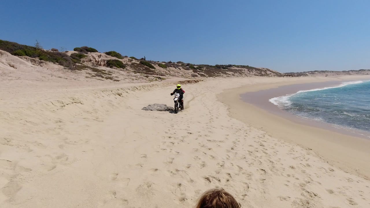 Motocross rider on a sandy beach near ocean waves