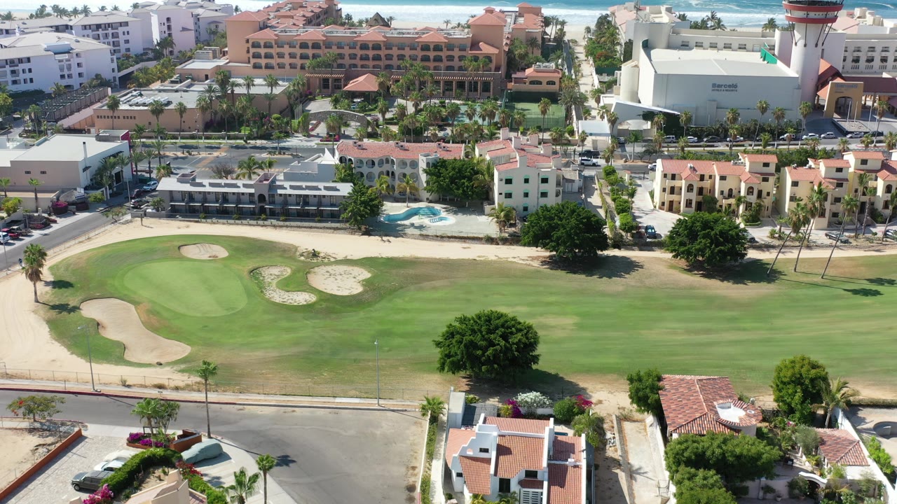 Golf green and sand bunkers with resort buildings across the road.